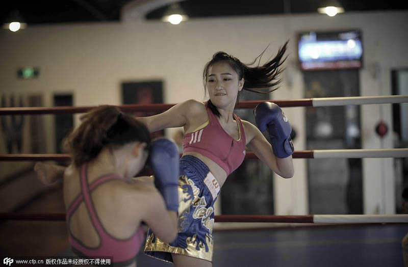 Dos compa?eras boxean juntas en un club de boxeo tailandés de Chongqing para aliviar el estrés del trabajo, el 24 de agosto de 2014. [Foto / PPC]