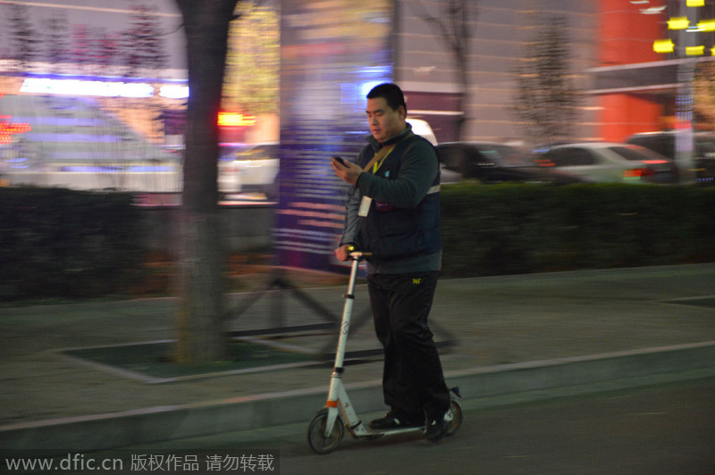 Li?Xiaodong?comprueba su teléfono en su scooter,?en?Shijiazhuang, provincia?de?Hebei,?el 17 de diciembre de?2014.?[Foto/IC]