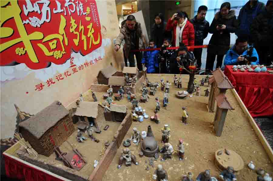 La gente observa las estatuillas de arcilla recreando un pueblo antiguo de Shandong. [Fotografía?por?Wang?Haibin/Asianewsphoto]