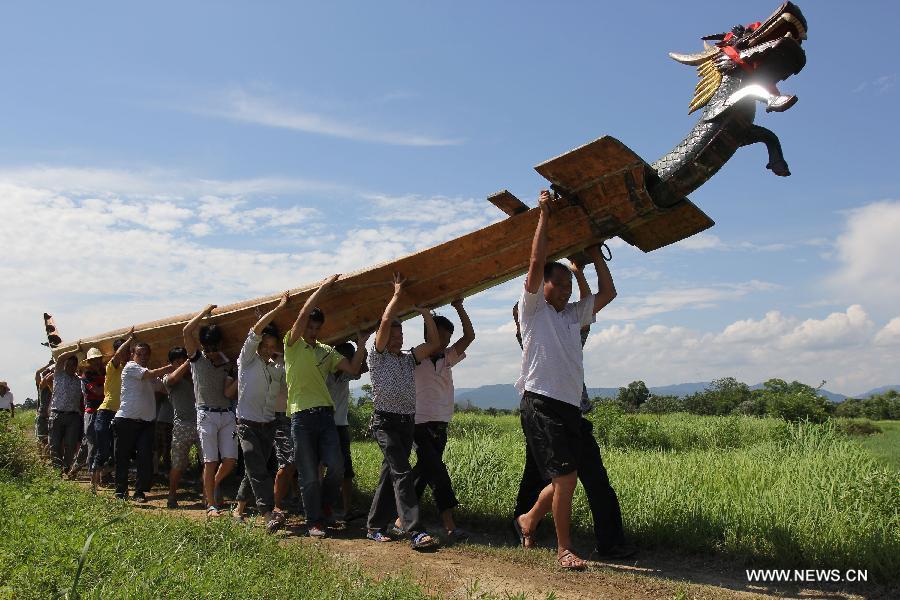 Varias personas trasladan su barco de dragón para la carrera celebrada en el río Xiaoshuihe para celebrar el Festival del Barco de Dragón en Yongzhou, provincia de Hunan, el 16 de junio de 2015. [Foto/Xinhua]