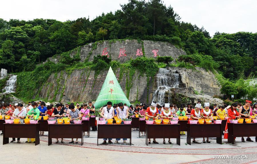 Residentes locales participan en un concurso de hacer Zongzi, una bola de masa de arroz glutinoso envuelta en hojas de bambú o de ca?a, para celebrar el Festival del Barco de Dragón en Zigui, provincia de Hubei, el 16 de junio de 2015.[Foto/Xinhua]