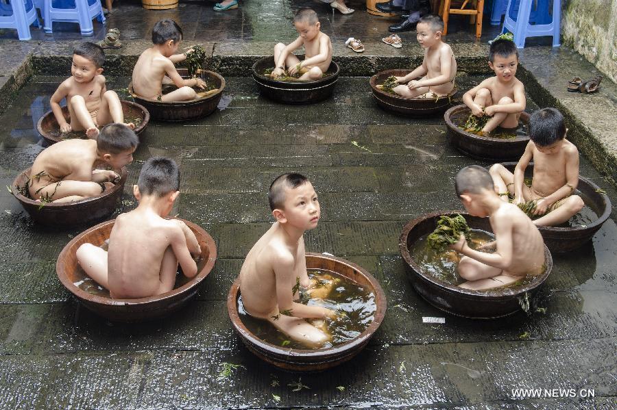 Los ni?os se ba?an en agua con ajenjo para celebrar el Festival del Barco de Dragón en Zigui, provincia de Hubei, el 16 de junio de 2015. [Foto/Xinhua]