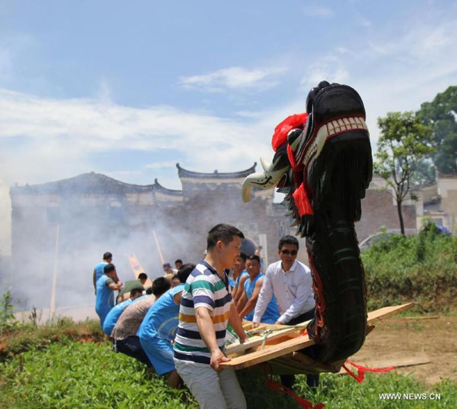 Varias personas trasladan su barco de dragón para la carrera celebrada en el río Xiaoshuihe para celebrar el Festival del Barco de Dragón en Yongzhou, provincia de Hunan, el 16 de junio de 2015. [Foto/Xinhua]