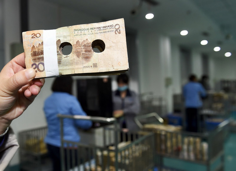 Los trabajadores perforan agujeros en los billetes para que queden inservibles el 3 de diciembre de 2015, en el Centro de Procesado de Billetes de Chengdu, provincia de Sichuan. (Foto/PPC)