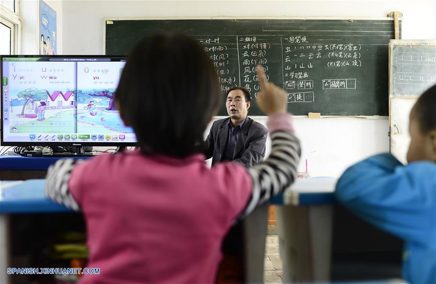 Imagen del 8 de septiembre de 2016 del maestro Hua Fulin (atrás), de 56 a?os de edad, el único profesor de la peque?a escuela de la villa de Kunlun, instruyendo a sus alumnos, en la villa de Kunlun de la ciudad de Haidong, provincia de Qinghai, en el noroeste de China. A unos 50 kilómetros de distancia del condado más cercano, la peque?a escuela de Kunlun ahora tiene sólo ocho alumnos y un maestro. (Xinhua/Zhang Hongxiang)