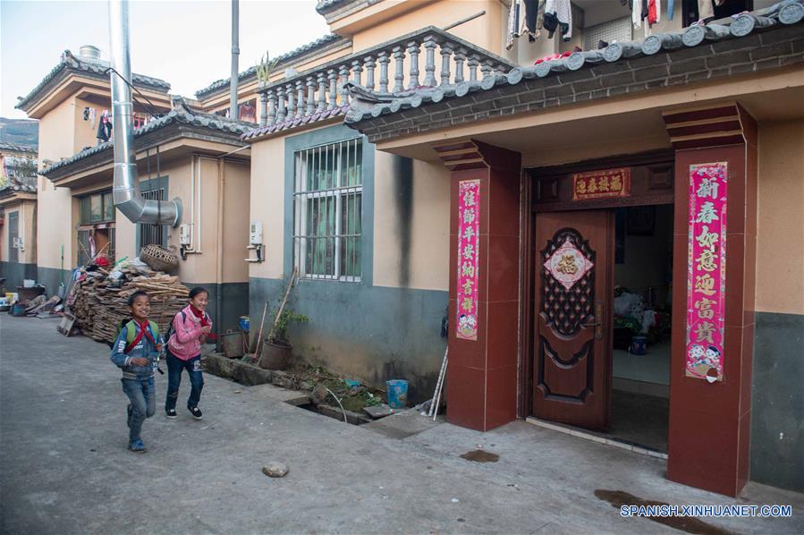 Unos ni?os pasan por su casa recientemente construida en el distrito de Mojiang el 12 de enero del presente a?o.  