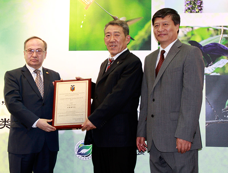 El fotógrafo Wang Jianguo recibe de manos del Dr. José María Borja, embajador de Ecuador en China, un reconocimiento por su obra. El Dr. Meng Qingjin, director del Museo de Historia Natural de Beijing, les acompa?a. (Foto: YAC)