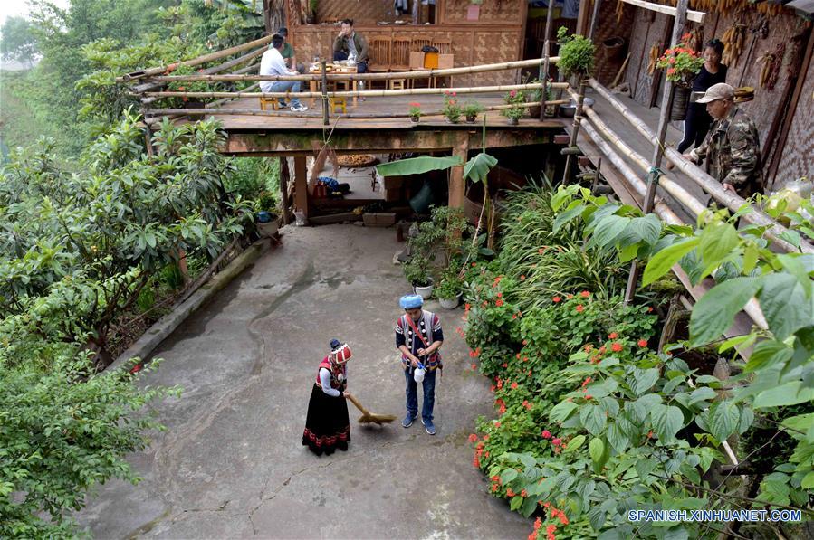 Imagen del 27 de mayo de 2017, de Yu Wulin (d-abajo) y su esposa Lu Binghua (i-abajo) limpiando su estancia familiar en el poblado de Laomudeng en el municipio étnico de Pihe Nu, en la provincia de Yunnan, en el suroeste de China. En 1996, Yu Wulin fue elegido para promover la cultura del grupo étnico Nu en Shanghai y se enamoró de la bailarina Lu Binghua. Después de regresar a su ciudad natal, se casaron y abrieron una estancia familiar para turistas. Crearon una marca de té y vendieron sus productos locales de té a mercados extranjeros. Gracias a la inspiración de la pareja, muchos residentes locales abrieron estancias familiares, y la vida ha cambiado en el poblado remoto. (Xinhua/Yang Zongyou)