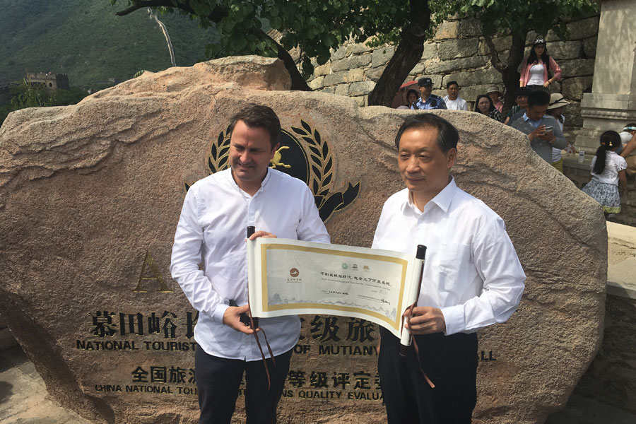 El primer ministro luxemburgués, Xavier Bettel, sostiene un pergamino con las palabras "El que no llega a la Gran Muralla no es un hombre de verdad", después de visitar la sección Mutianyu de la Gran Muralla de Beijing, el 11 de junio de 2017. Foto de Jiang Chenglong para China Daily