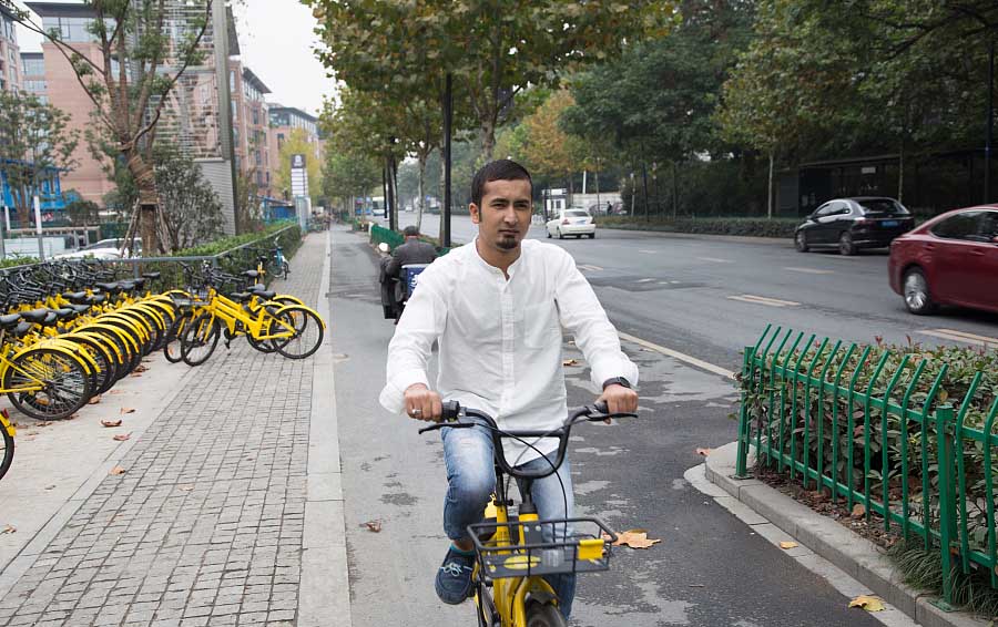 Nayeem Hafeez monta en una bicicleta compartida Ofo en Hangzhou, provincia de Zhejiang, el 12 de noviembre de 2017. [Foto / VCG]