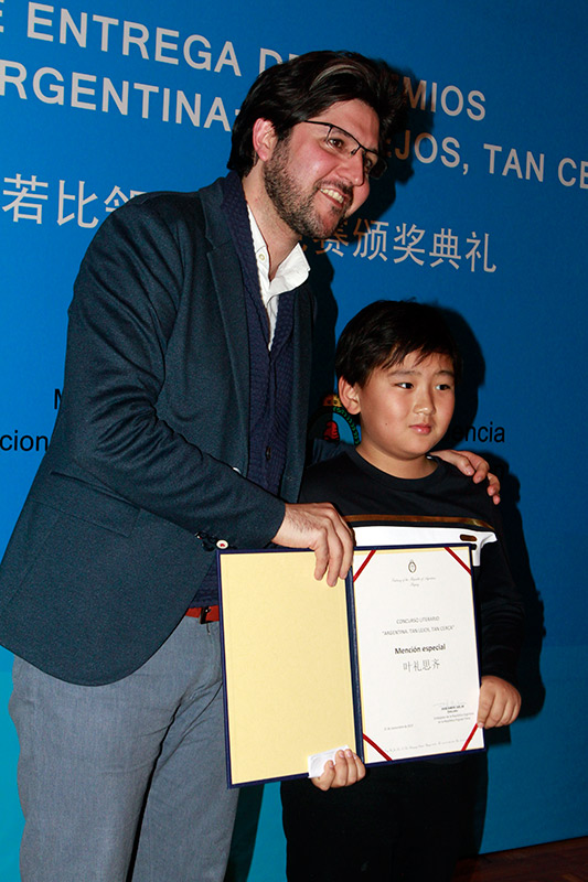 Guillermo Bravo, profesor y escritor argentino residente en Beijing, entrega una mención especial a un ni?o chino durante la premiación del primer concurso literario “Argentina: tan lejos, tan cerca”. Beijing, 21 de noviembre del 2017. (Foto: YAC)