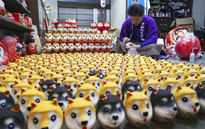 Un artesano japonés trabaja en mu?ecos daruma con rostros de perros, el animal regente del zodíaco chino durante el 2018, 24 de noviembre del 2017. [Foto: IC]