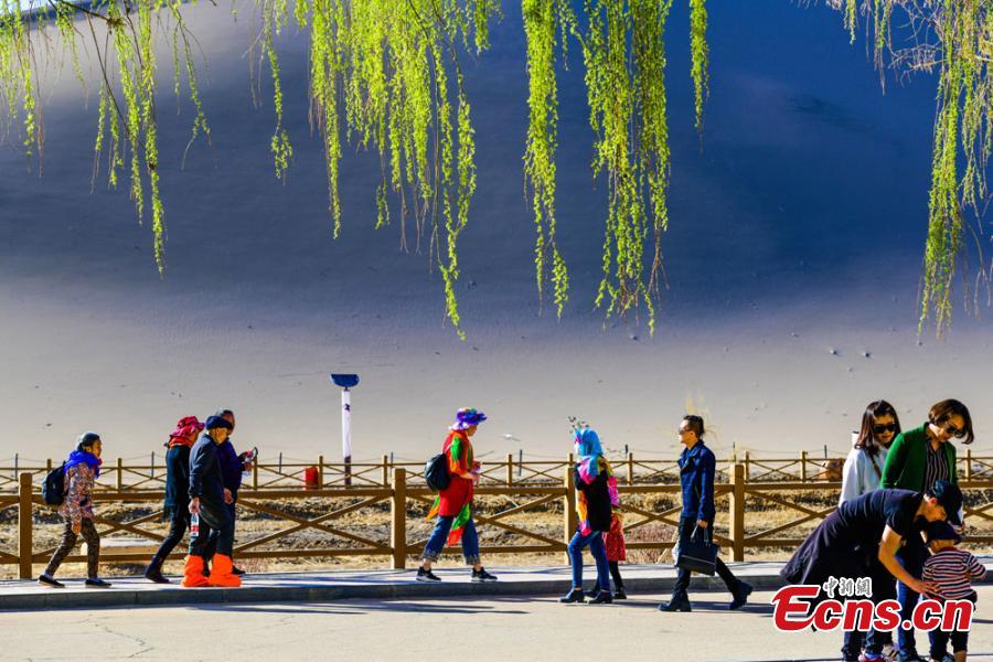 Los turistas visitan las monta?as arenosas cantantes de Dunhuang 