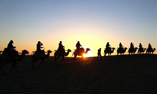 Los turistas visitan la Monta?a Mingsha y el Lago de la Luna Creciente en Gansu 