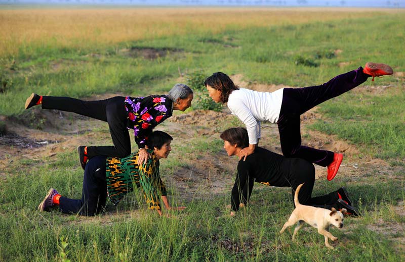 Temprano en la ma?ana, cuatro aldeanas practican yoga en el campo. [Foto: Zhu Xingxin/China Daily]