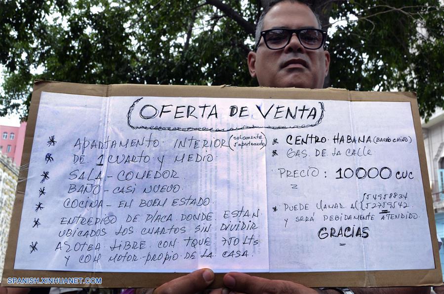 LA HABANA, octubre 7, 2018 (Xinhua) -- Imagen del 6 de octubre de 2018, de un hombre sosteniendo un cartel que promueve la venta de una vivienda, en la Bolsa de Permuta de Prado, en La Habana, Cuba. La conocida Bolsa de Permuta de Prado es un espontáneo lugar de intercambio de casas ubicado en el Paseo del Prado, una de las más viejas avenidas de la capital cubana. Allí, bajo la sombra de frondosos árboles, cientos de personas se dan cita todos los fines de semana en un informal mercado de viviendas donde, con carteles escritos a mano, muchos promueven los inmuebles que ofrecen y lo que necesitan. Los llamados "corredores de permutas" o "permuteros", como también se les conoce popularmente, son personas que se dedican a gestionar los intercambios de vivienda y cobran por esos servicios una parte del dinero involucrado en la transacción. (Xinhua/Joaquín Hernández)