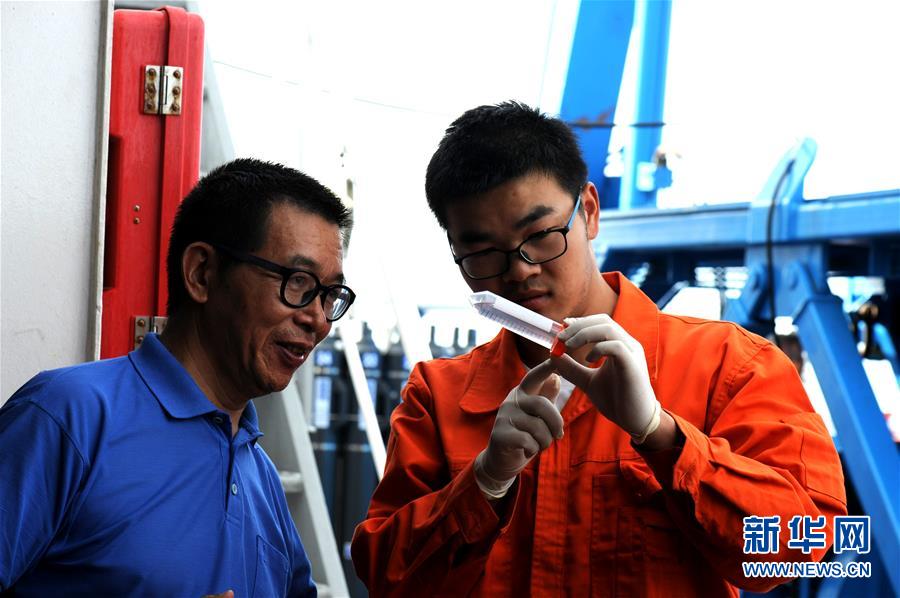 Cui Weicheng (izquierda), el comandante principal del equipo de investigación científica del robot marino "Rainbow Fish", y un miembro del equipo de expedición (derecha) observan una muestra con seres vivos capturados en la fosa. (Foto tomada el 12 de diciembre).