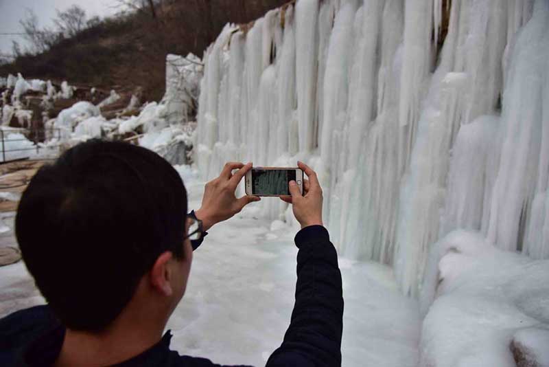 Un turista toma fotos de una cascada congelada en la monta?a Wuzhishan de Handan, provincia de Hebei, 15 de enero del 2019. [Foto: Yang Yanzhong/ Chinadaily.com.cn]