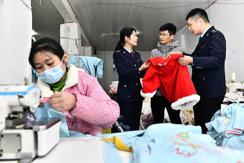 Miembros del personal de la oficina local de impuestos explican políticas preferenciales fiscales a Hu Chunqing. [Foto: Xinhua]