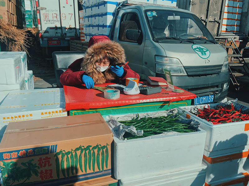 Wang Lijun, una vendedora de 43 a?os que lleva trabajando en el mercado Xinfadi desde hace más de 15 a?os, regatea con su socio por teléfono móvil. (Pueblo en Línea / Kou Jie)