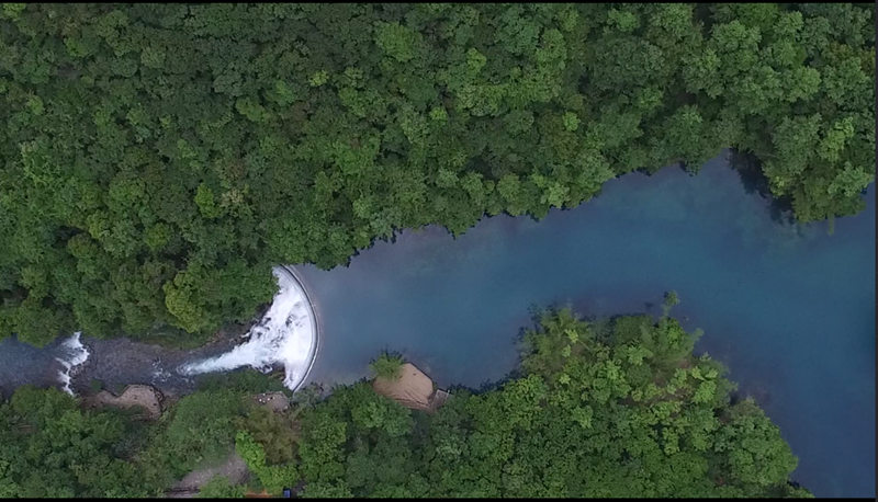 El verde vibrante del espeso bosque y el azul zafiro del agua refulgen en la zona turística de Libo, provincia de Guizhou. [Foto: Yao Xiandun/ Chinadaily]