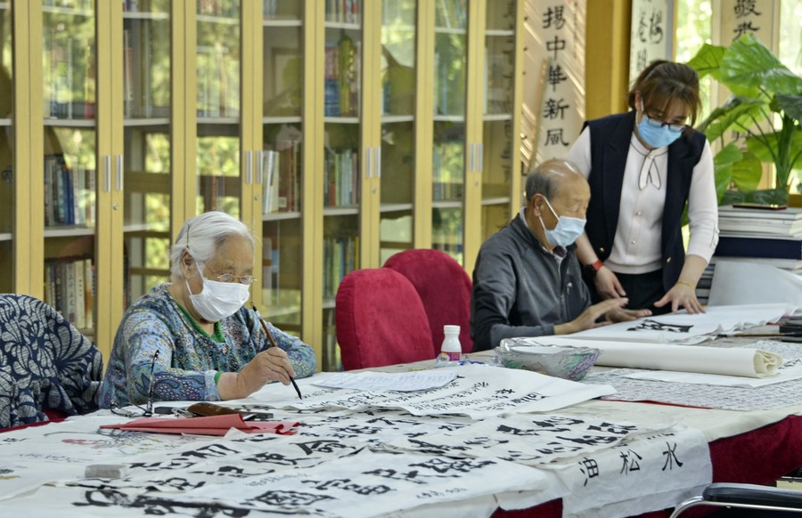 Ancianos practican caligrafia acompa?ados por una trabajadora en un asilo de ancianos Sijiqing en el distrito de Haidian de Beijing, la capital de China, el 10 de mayo de 2020. (Xinhua/Li Xin)