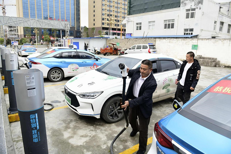 Un taxista carga su automóvil eléctrico en una estación de carga en el condado Anlong, en la provincia de Guizhou, suroeste de China. La empresa de taxis para la que trabaja el conductor ya puso en servicio 70 coches eléctricos en 2020. (Liu Chaofu / Pueblo en Línea)