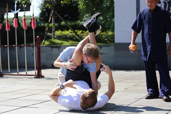   Per Marcus Andersson (en el suelo), miembro del grupo conjunto de entrevistas e investigación del Foro de Cooperación de Medios Belt and Road 2024, hace una demostración de lucha libre por sumisión. (Foto de Liu Xiaoli)